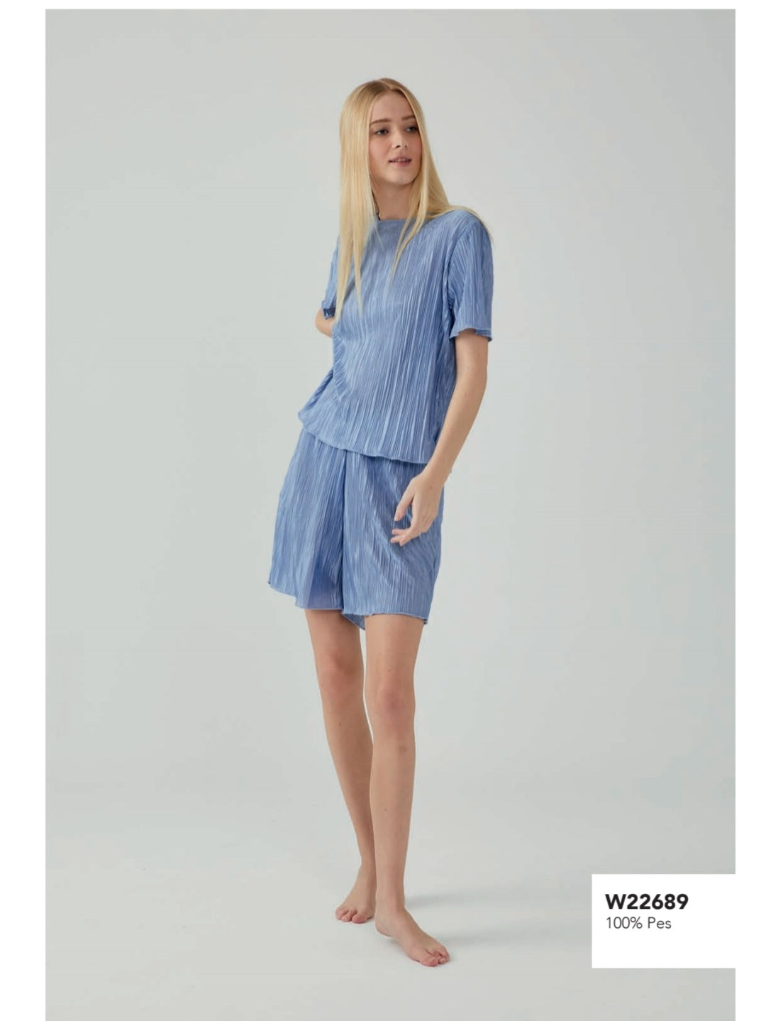  Woman wearing Popjammies Blue Pleated Pajama Set, featuring a short-sleeve top and matching shorts made from 100% polyester.