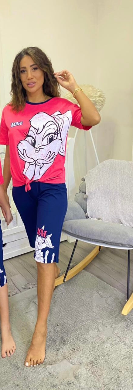 Woman wearing a pink short-sleeve top with a white bunny print and tie-front detail, paired with navy capri pantacour with a bunny graphic 
