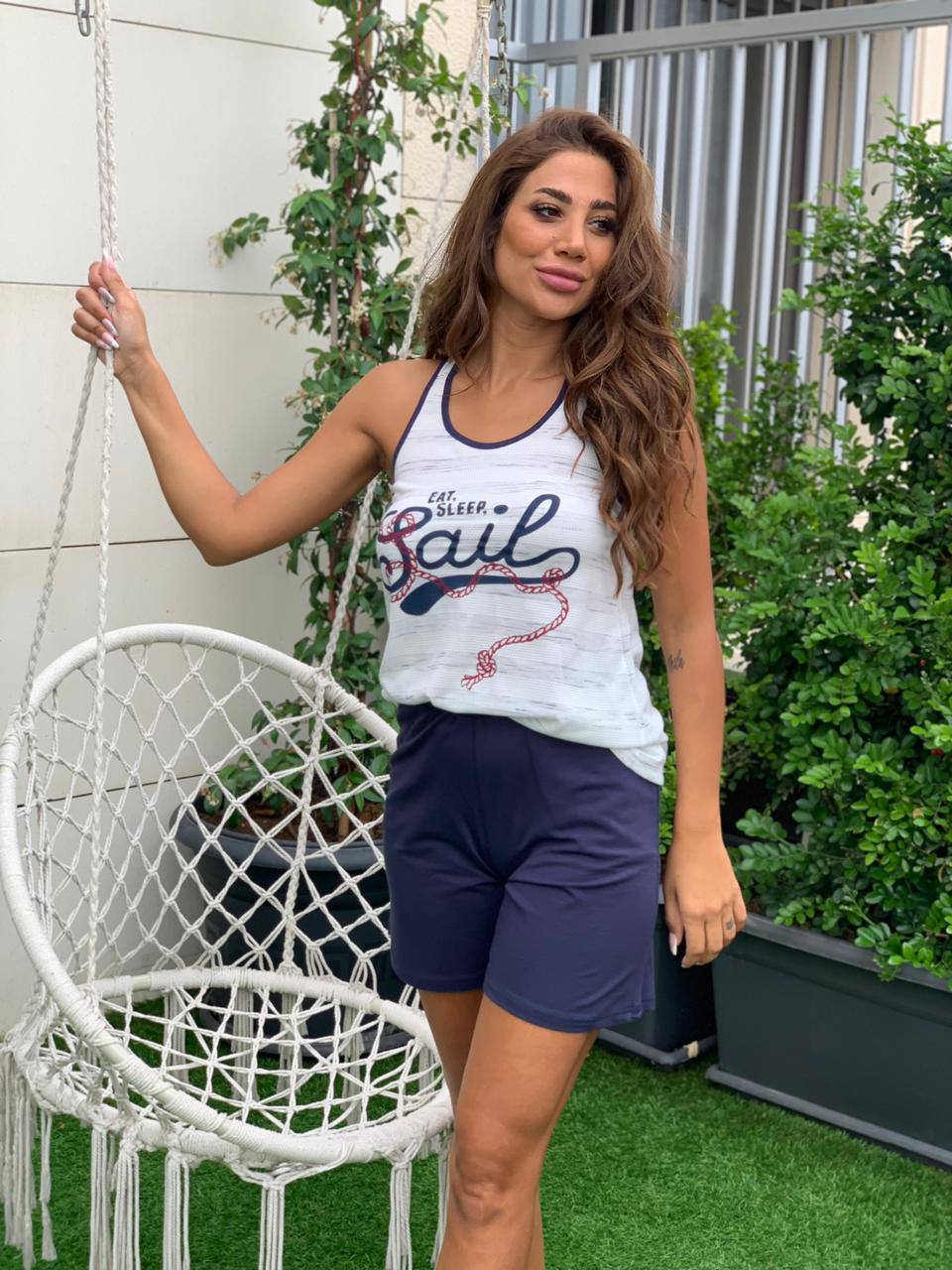  Woman wearing Popjammies Eat Sleep Sail Tank Top and Shorts Pyjama Set with a nautical graphic tank top and navy shorts.