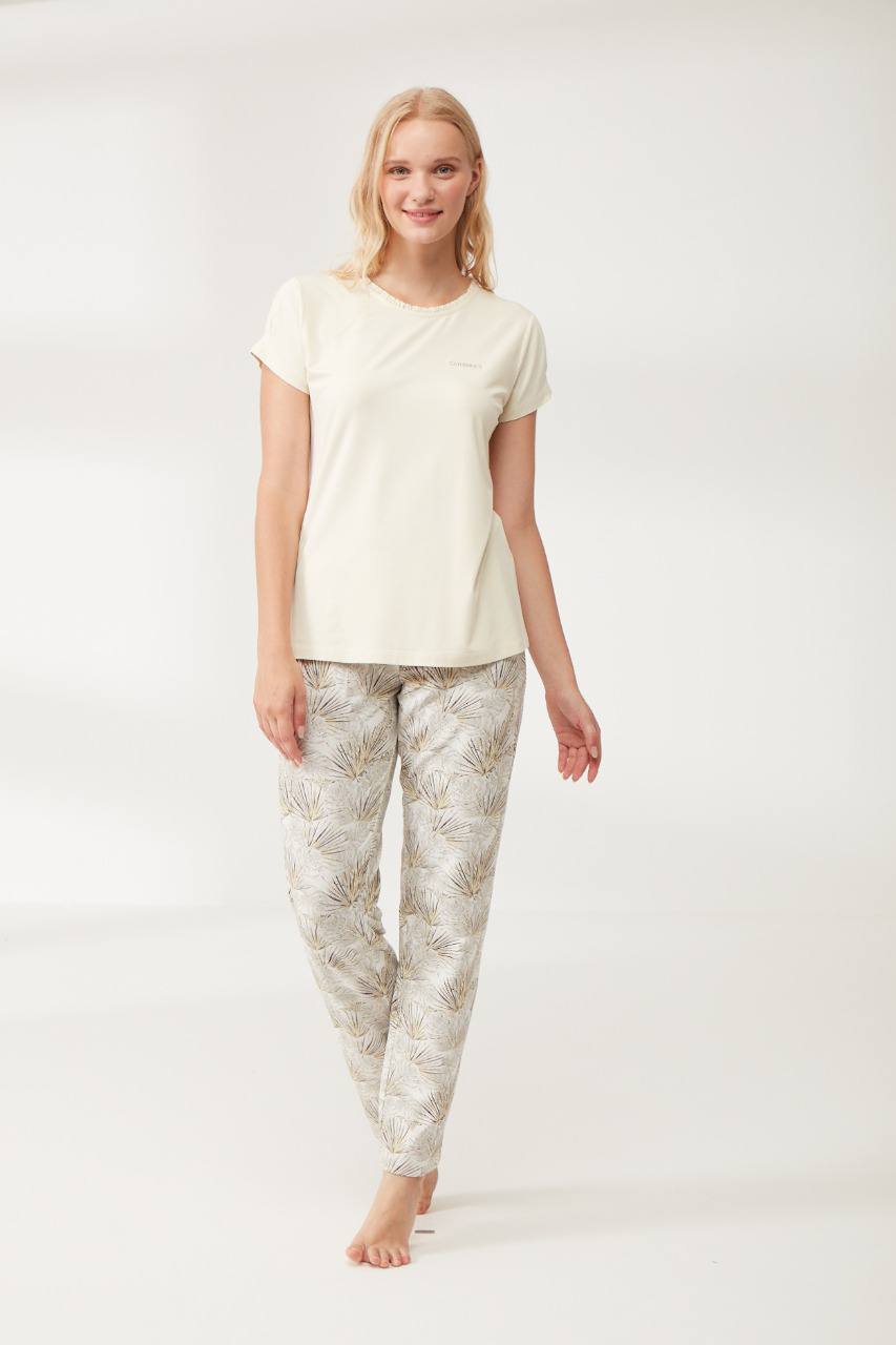 Woman wearing Popjammies white short-sleeve top and botanical print pants in a studio setting.