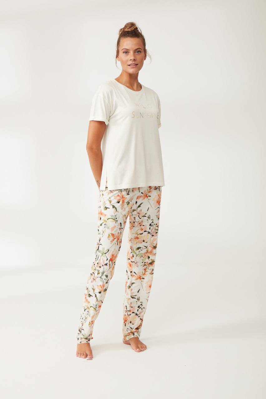 Woman wearing Popjammies white "Hello Sunshine" short-sleeve top and floral print pants in a studio setting.